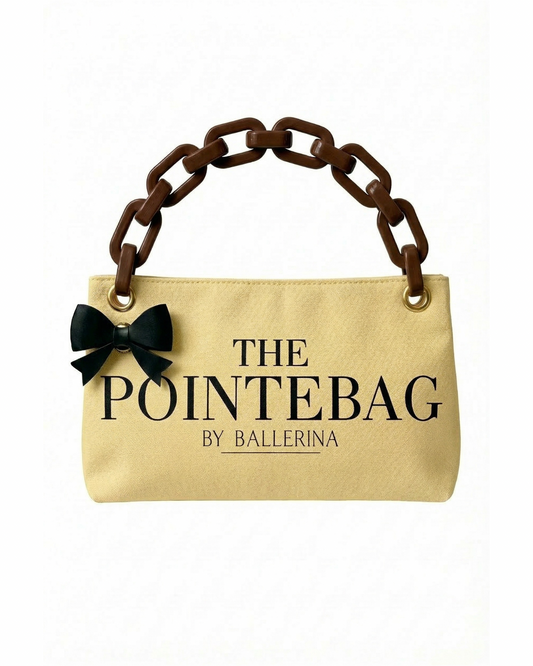 The front of our Butter Yellow Classic PointeBag | Pointe Shoes Bag in Butter Yellow Color with the logo PointeBag By Ballerina in black color. There is the classic black bow clip and coffee color plastic chain strap.